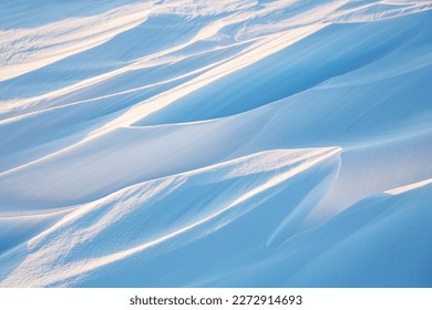 Snow texture. Wind sculpted patterns on snow surface. Wind in the tundra and in the mountains on the surface of the snow sculpts patterns and ridges (sastrugi). Arctic, Polar region. Winter background