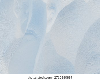 Snow texture. Wind sculpted patterns on snow surface. Wind in the tundra and in the mountains on the surface of the snow sculpts patterns and ridges (sastrugi). Arctic, Polar region. Winter background