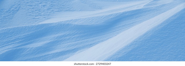 Snow texture. Wind sculpted patterns on snow surface. Wind in the tundra and in the mountains on the surface of the snow sculpts patterns and ridges. Arctic, Polar region. Winter panoramic background.
