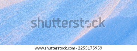 Snow texture. Wind sculpted patterns on snow surface. Wind in the tundra and in the mountains on the surface of the snow sculpts patterns and ridges. Arctic, Polar region. Winter panoramic background.