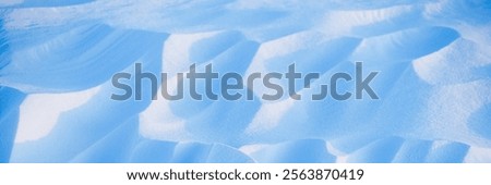 Snow texture. Wind sculpted patterns on snow surface. Wind in the tundra and in the mountains on the surface of the snow sculpts patterns and ridges. Arctic, Polar region. Winter panoramic background.