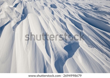 Snow texture. Wind sculpted patterns on snow surface. Wind in the tundra and in the mountains on the surface of the snow sculpts patterns and ridges (sastrugi). Arctic, Polar region. Winter background
