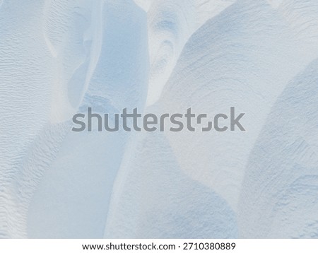 Snow texture. Wind sculpted patterns on snow surface. Wind in the tundra and in the mountains on the surface of the snow sculpts patterns and ridges (sastrugi). Arctic, Polar region. Winter background