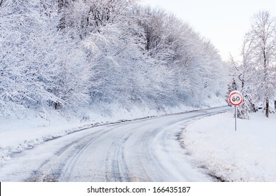 Snow Tracks On A Country Road And 60 Mph/km Signs.