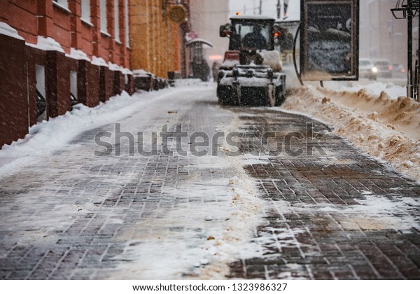 snow tractor and municipal excavator
with a large bucket removes snow on the street, fallen during the
winter cold, the work of public services of the
city