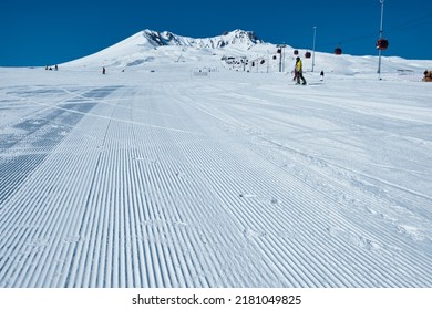 Snow velvet of a ski piste. Snow groomer tracks on ski slope. Morning groomed snow. Ski piste prepared by snowcat is ready for skiers and snowboarders 