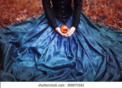 Snow White princess with the famous red apple. Girl holds a ripe Apple sitting on lap