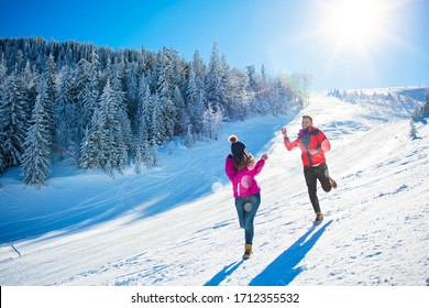 Snowball Fight. Winter Couple Having Fun Playing In Snow Outdoors. Young Joyful Happy Multi-racial Couple.