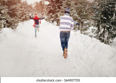 Snowball Fight. Winter Loving Couple Having Fun Playing Catch Up Outdoors. Young Joyful Happy Couple In Love