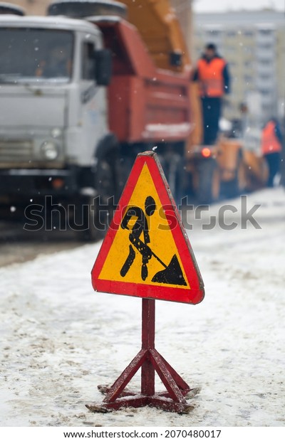 Snowblower clear\
freezing winter road with snow and ice.Snow-plow remove snow from\
the city street.Warning road sign.Winter service vehicle snow\
blower work.Cleaning snowy frozen\
roads