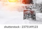 snowblower removes snow, a man cleans the yard outside