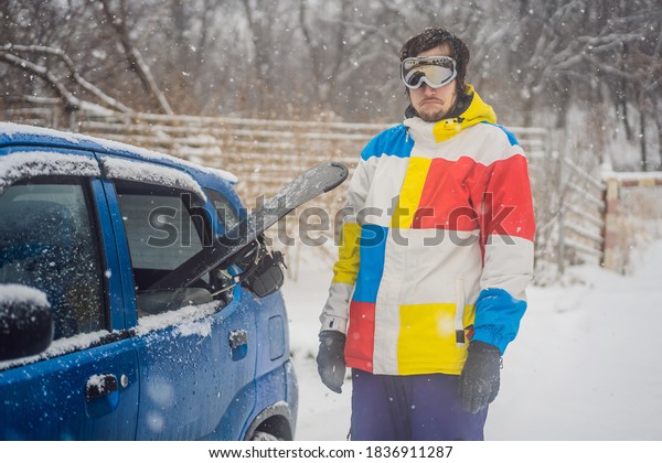 The snowboard\
does not fit into the car. A snowboarder is trying to stick a\
snowboard into a car. Humor,\
fun