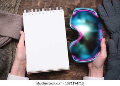 Snowboard Googles And Blank Notepad With Copy Space In Female Hands. Snowboarding Tips Mock Up.