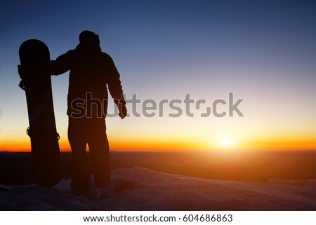 Snowboard and ski concept with snowboarder on mountain top at sunset time. Space for text