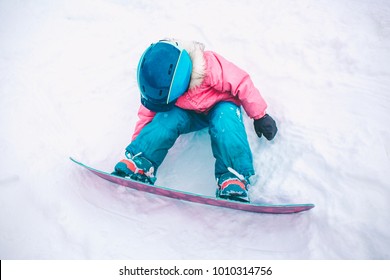 Snowboard Winter Sport. Little Kid Girl Playing With Snow Wearing Warm Winter Clothes. Winter Background.