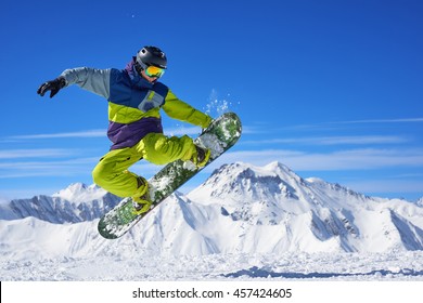 Snowboarder in bright sportswear doing trick against of beautiful mountains