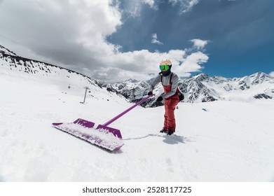 Snowboarder building a ski jump outdoors near a ski resort in the mountains, shaping a snowboard park. Sunny winter day - Powered by Shutterstock