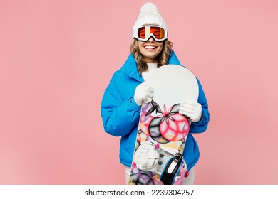 Snowboarder excited woman wear blue suit goggles mask hat ski padded jacket hold snowboard behind neck isolated on plain pastel pink background. Winter extreme sport hobby weekend trip relax concept