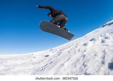 Snowboarder Executing A Radical Jump Against Blue Sky.