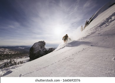 Snowboarder female riding on clear snow powder from steep slope, winter sunny day, free-riding in ski resort