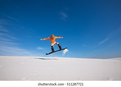 Snowboarder is flying over the sand dune. Snowboarding training in summer season. Sand boarding in desert. - Powered by Shutterstock