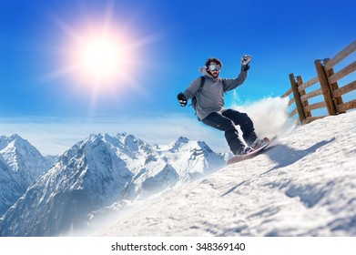 Snowboarder freerider. Snowboarder man holding snowboard in the air jumping with mountains on background