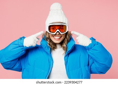 Mujer divertida Snowboarder usa traje azul gafas máscara sombrero raqueta de la chaqueta acolchada dedo índice en gafas aisladas en un fondo rosa pastel claro. Concepto de relajación del viaje de fin de semana de hobby deportivo extremo invierno