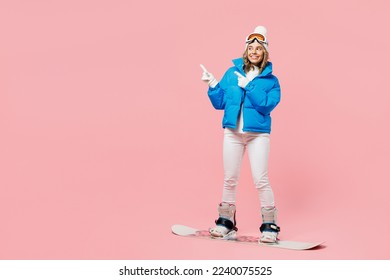 Snowboarder fun woman wear blue suit goggles mask hat ski padded jacket snowboarding point finger aside isolated on plain pastel pink background. Winter extreme sport hobby weekend trip relax concept - Powered by Shutterstock