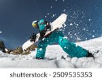 Snowboarder is having fun and posing with snowboard in cloud of powder snow at ski resort