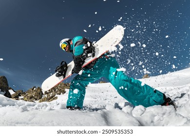 Snowboarder is having fun and posing with snowboard in cloud of powder snow at ski resort