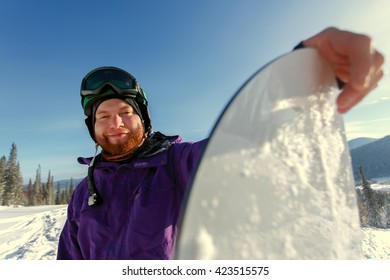 Snowboarder Holds Snowboard On Top Of Hill, Close Up Portrait