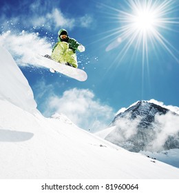 Snowboarder at jump inhigh mountains at sunny day.