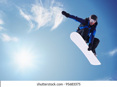 Сноубордист прыгает против голубого неба