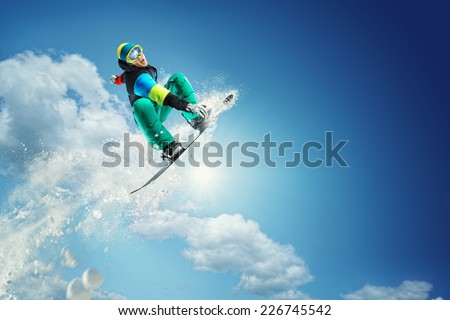 Snowboarder jumping against blue sky 