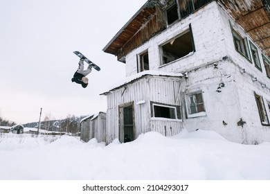 Snowboarder Jumping Flip From Abandoned Building. Street Snowboarding Style