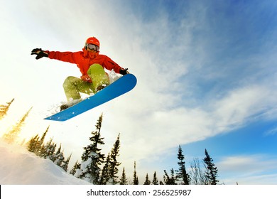 Сноубордист прыгает по воздуху с глубоким голубым небом в фоновом режиме