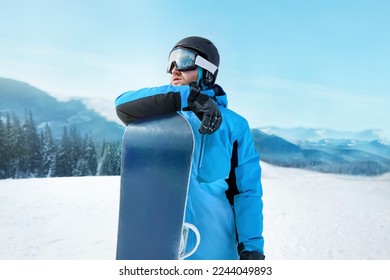 Snowboarder Of Man At Ski Resort On The Background Blue Sky,  Hold Snowboard. Wearing Ski Glasses. Ski Goggles  With The Reflection Of Snowed Mountains