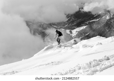 Snowboarder on snowy off-piste slope, high winter mountains in fog. Caucasus Mountains, Georgia, region Gudauri. Black and white toned image.