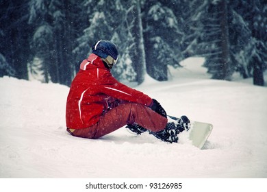 Snowboarder sitting on the snow and watching beautiful nature