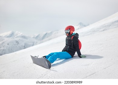 Snowboarder sitting in the snow, high mountain landscape - Powered by Shutterstock