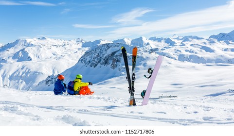 snowboarder and skiier sitting on snow and see at mountains - Powered by Shutterstock