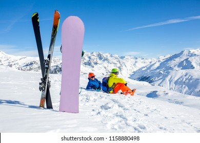 Snowboarder And Skiier Sitting On Snow And See At Mountains