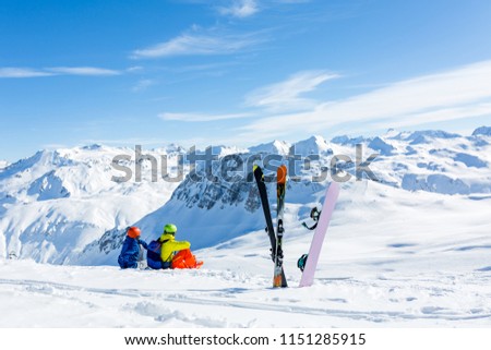 snowboarder and skiier sitting on snow and see at mountains