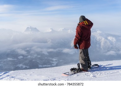 Snowboarder is standing on top of the mountain and looking at the beautiful scenery. Taken in Revelstoke Ski Resort, British Columbia, Canada. Adventure, holiday concept - Shutterstock ID 784355872