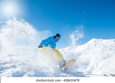 Snowboarder In Winter Sports Gear Riding Down The Slope At A Ski Resort