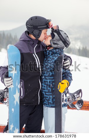 snowboarders couple kiss each other on the background of mountains