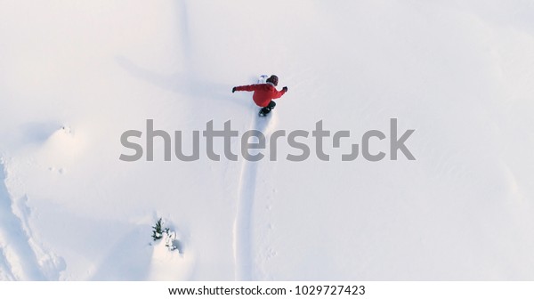 Snowboarding Overhead Top Down View of
Snowboarder Riding Through Fresh Powder Snow Down Ski Resort or
Backcountry Slope - WInter Extreme Sports
Background