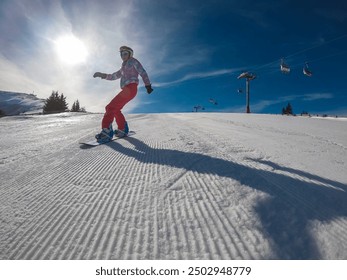 Snowboarding woman racing down mountain slope in ski resort Koralpe, Lavanttal, Carinthia Styria, Austria. Winter wonderland  alpine Austrian Alps. Freshly groomed ski run. Parallel lines from snowcat - Powered by Shutterstock