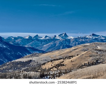 Snow-capped mountain peaks and rolling hills under a clear blue sky. This scenic view captures the rugged beauty of Colorado’s high-altitude terrain in winter. - Powered by Shutterstock