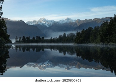 Snow-Capped Mountain Range Reflected on a Misty Lake at Sunrise, Lake Matheson, New Zealand